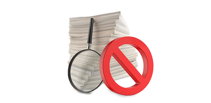 A stack of papers with a magnifying glass stacked against the paper and a red circle and a strike through it.